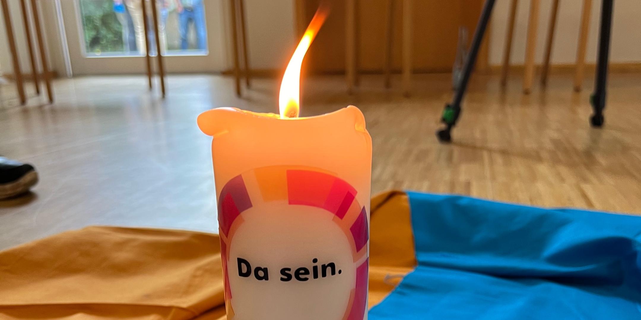 Brennende Kerze mit Logo des Pastoralen Raums DaSein