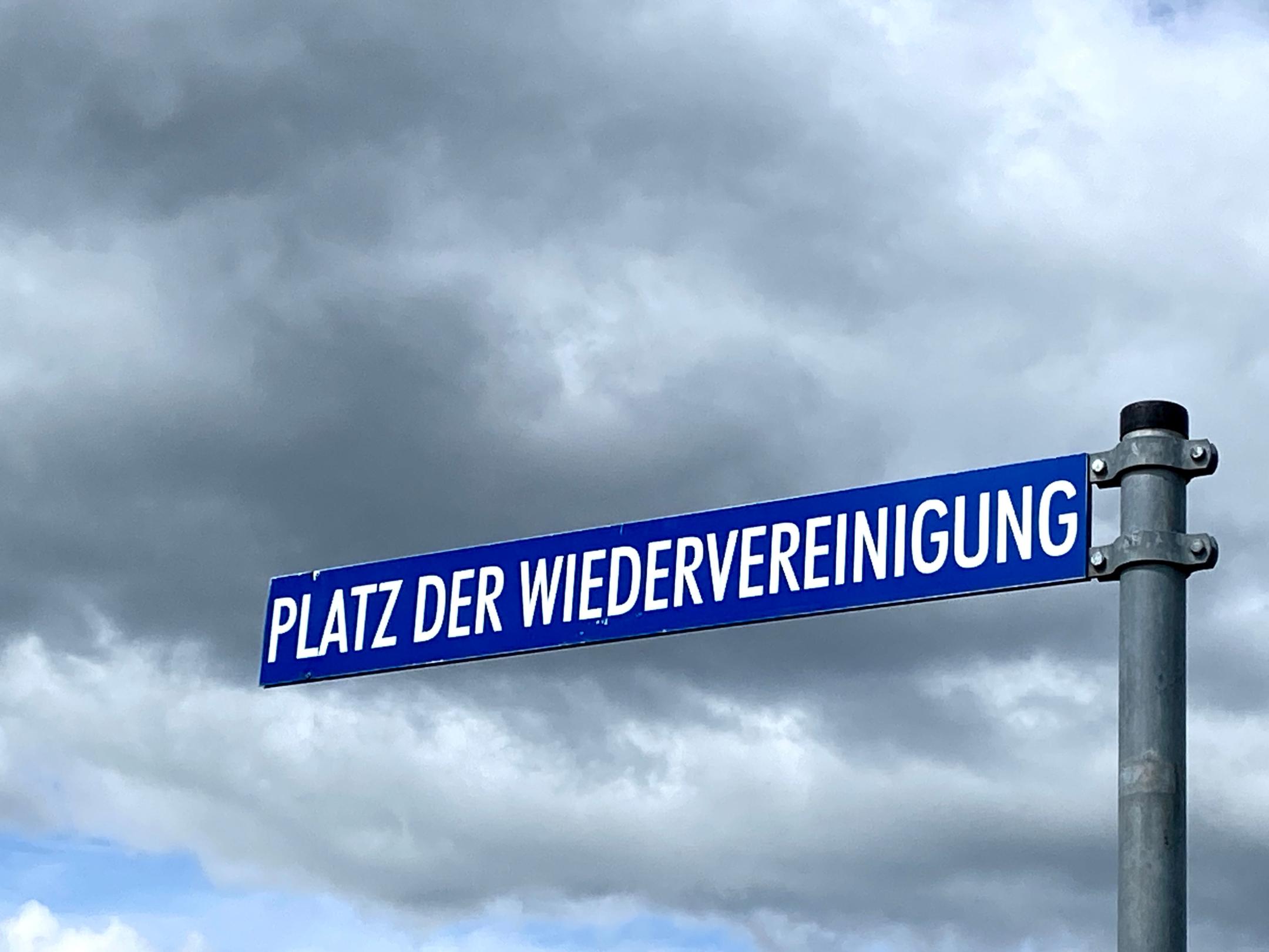 Ein Straßenschild 'Platz der Wiedervereinigung'