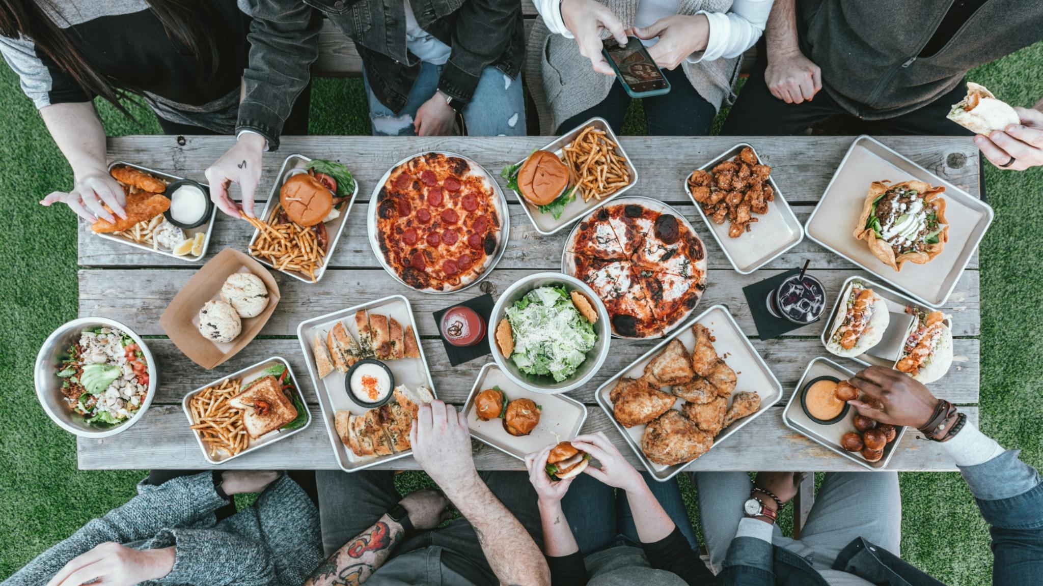 Mehrere Personen sitzen zusammen an einem Tisch und essen, von oben fotografiert